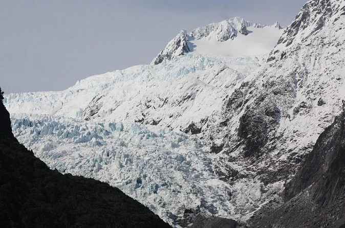 El glaciar Franz Josef visto desde el valle, con su cascada de hielo cayendo entre paredes de roca oscura