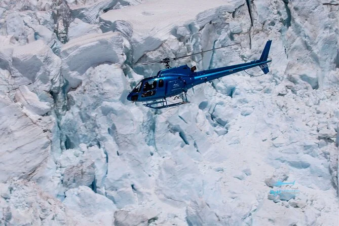 A helicopter flying low over deeply crevassed glacier ice